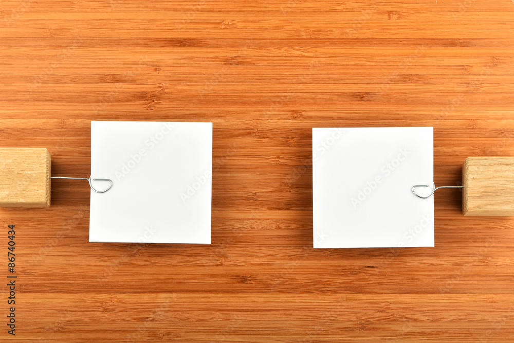 Two paper notes with holders in different directions on wood Two paper notes with holders in different directions on wood