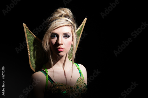 Canvas Print Young blonde woman dressed as fairy on dark background