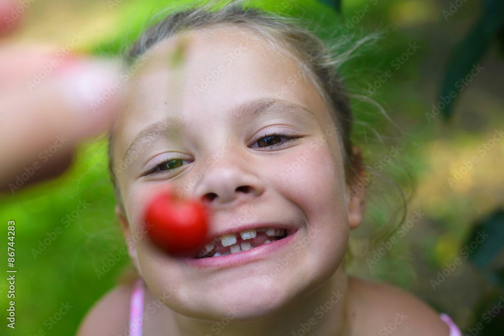 Closeup portrait little funny girl eating cherry in cherry garden Closeup portrait little funny girl eating cherry in cherry garden
