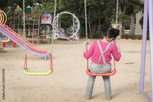 Lonely girl sitting on chain swing