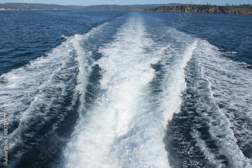 Spindrift of boat on ocean water at coast