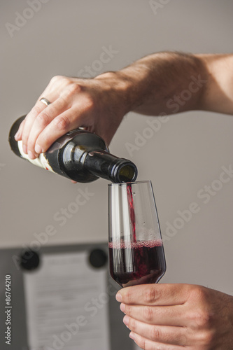Man pouring red wine from bottle into a glass