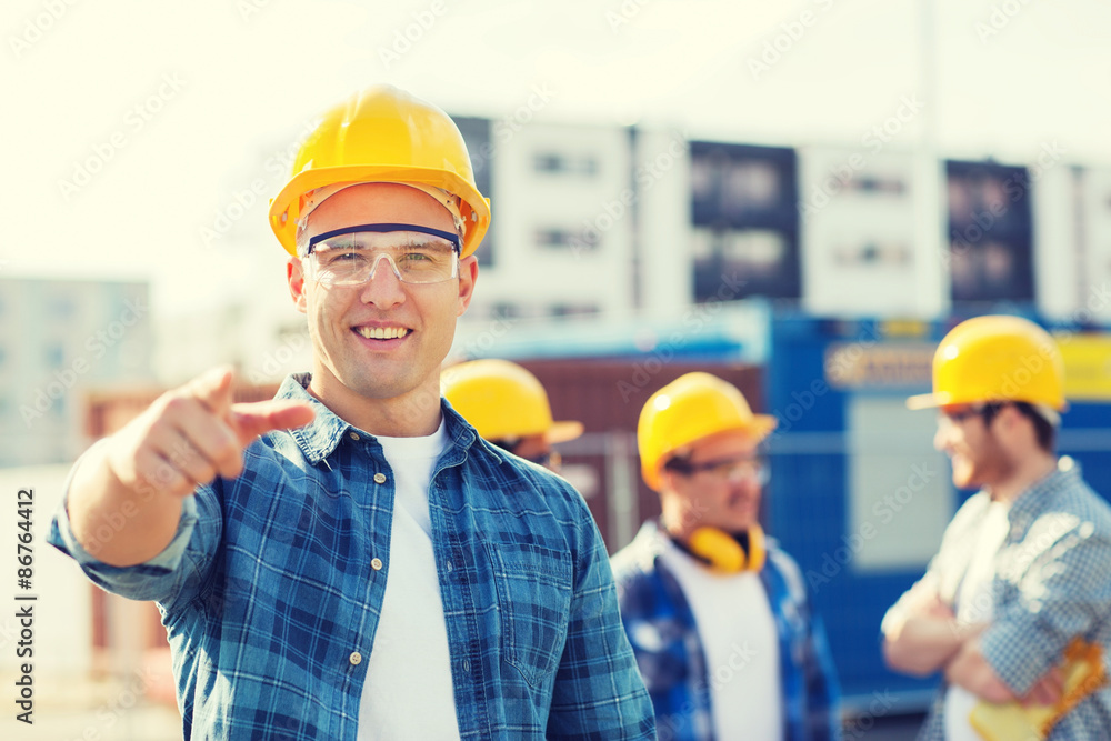 group of smiling builders in hardhats outdoors group of smiling builders in hardhats outdoors