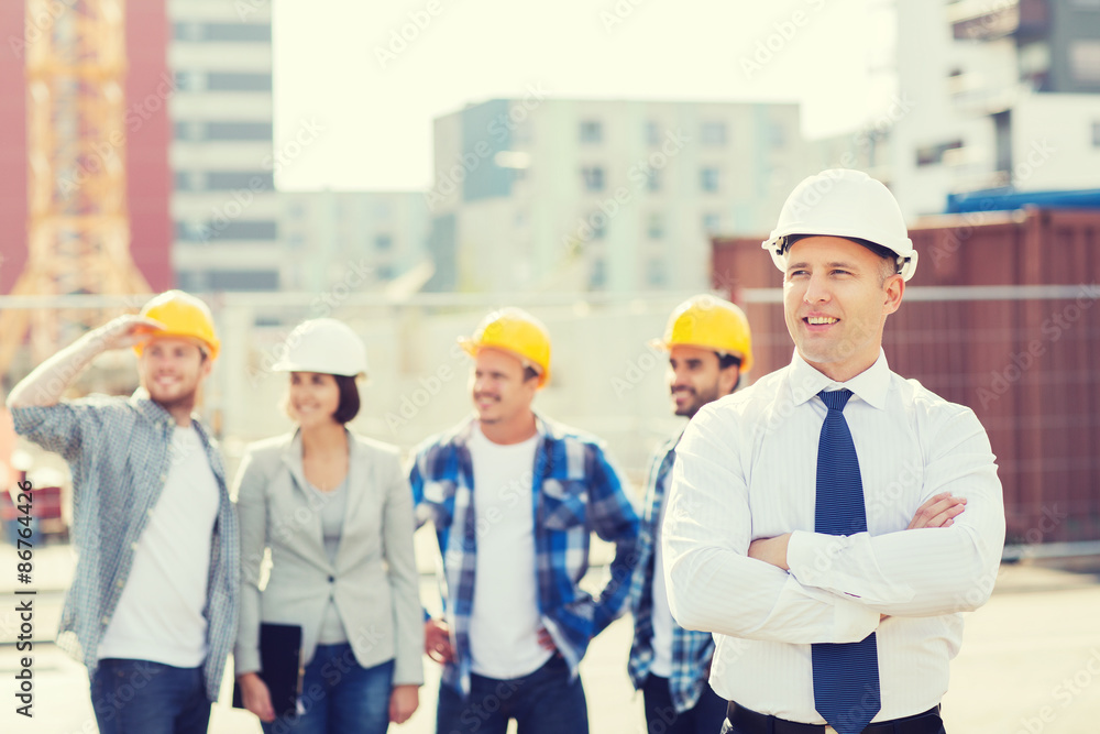 group of smiling builders in hardhats outdoors group of smiling builders in hardhats outdoors