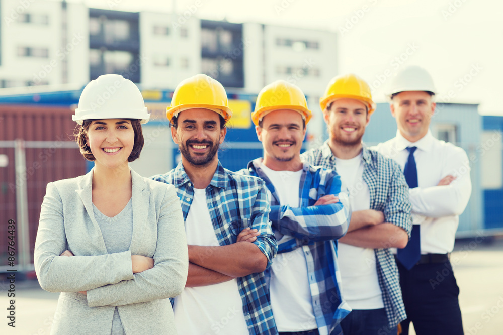 group of smiling builders in hardhats outdoors group of smiling builders in hardhats outdoors