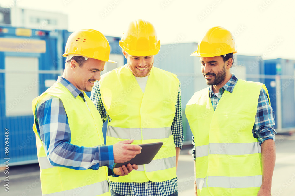smiling builders in hardhats with tablet pc smiling builders in hardhats with tablet pc