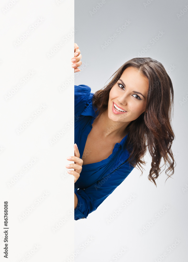 Young happy smiling woman showing blank signboard, on grey Young happy smiling woman showing blank signboard, on grey