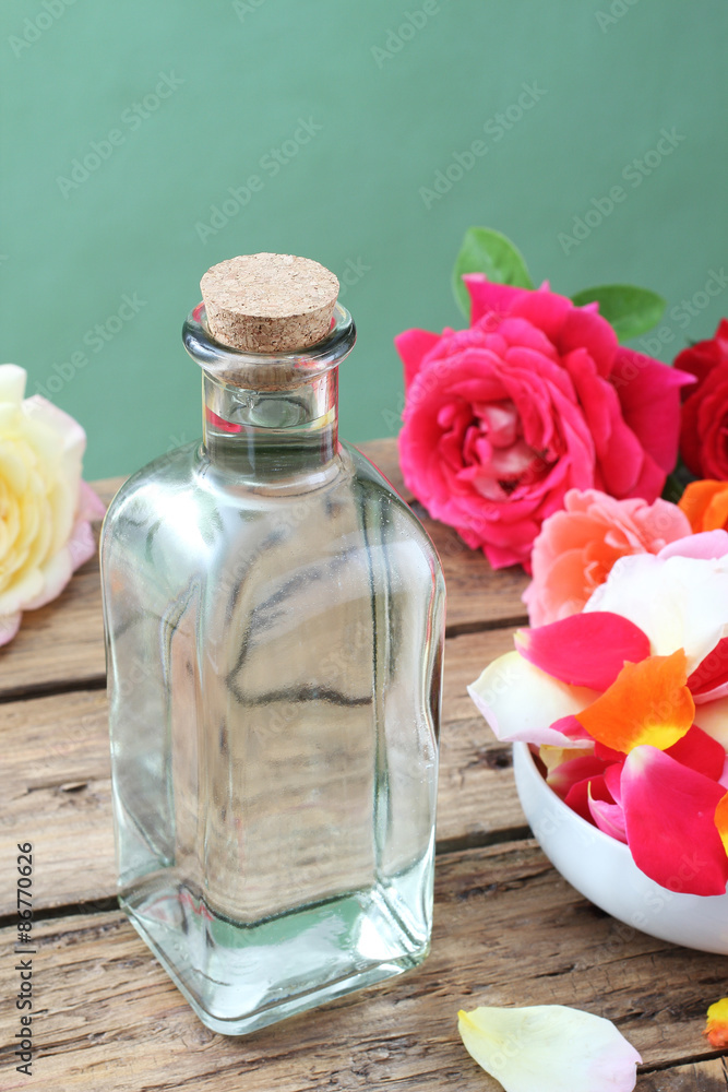 acqua di fiori con petali di rosa in bottiglia di vetro sfondo rustico  Stock Photo | Adobe Stock