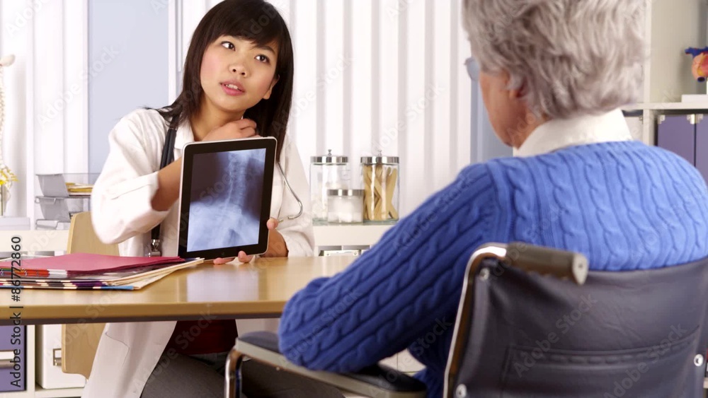 Asian doctor explaining neck x-ray to elderly patient Asian doctor explaining neck x-ray to elderly patient