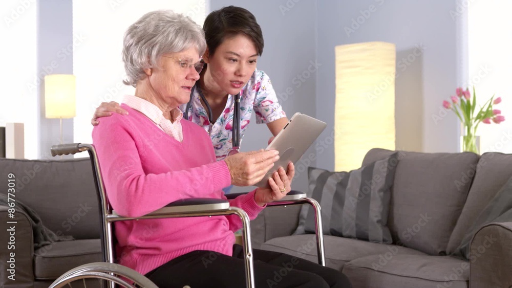 Elderly patient and Asian nurse talking with tablet Elderly patient and Asian nurse talking with tablet
