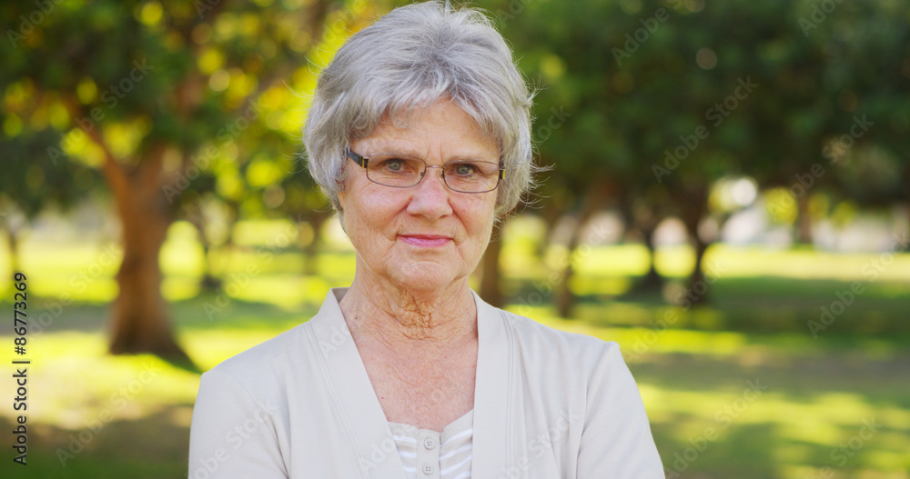 Senior woman standing in the park looking at camera Senior woman standing in the park looking at camera