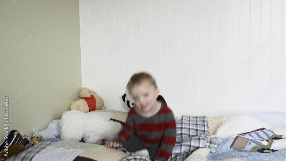 A toddler jumping on his bed in his bedroom A toddler jumping on his bed in his bedroom