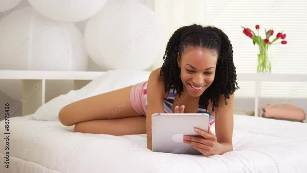 Black woman smiling at camera with tablet in bedroom Black woman smiling at camera with tablet in bedroom
