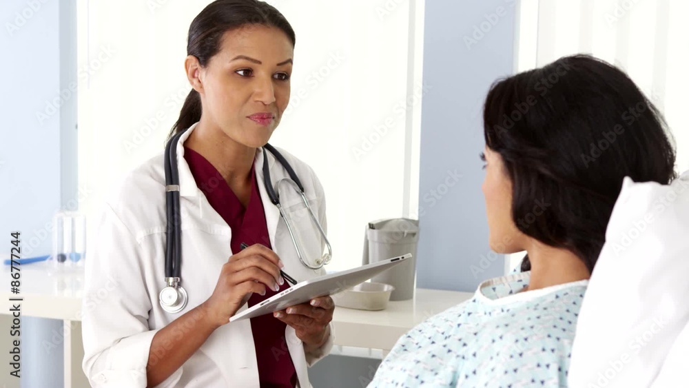 Female African doctor talking to Hispanic patient using tablet computer Female African doctor talking to Hispanic patient using tablet computer