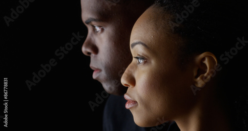 Dramatic side view of two young African American people on black background
