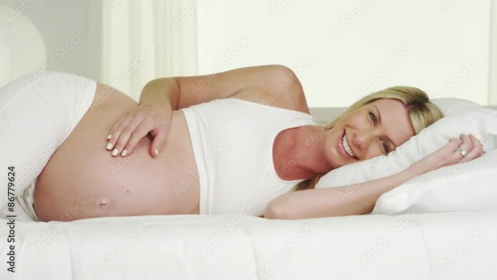 Beautiful pregnant woman lying on bed smiling Beautiful pregnant woman lying on bed smiling