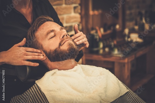 Hairstylist applying after shaving lotion in barber shop photo