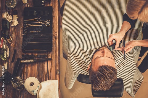 Client during beard and moustache grooming in barber shop photo