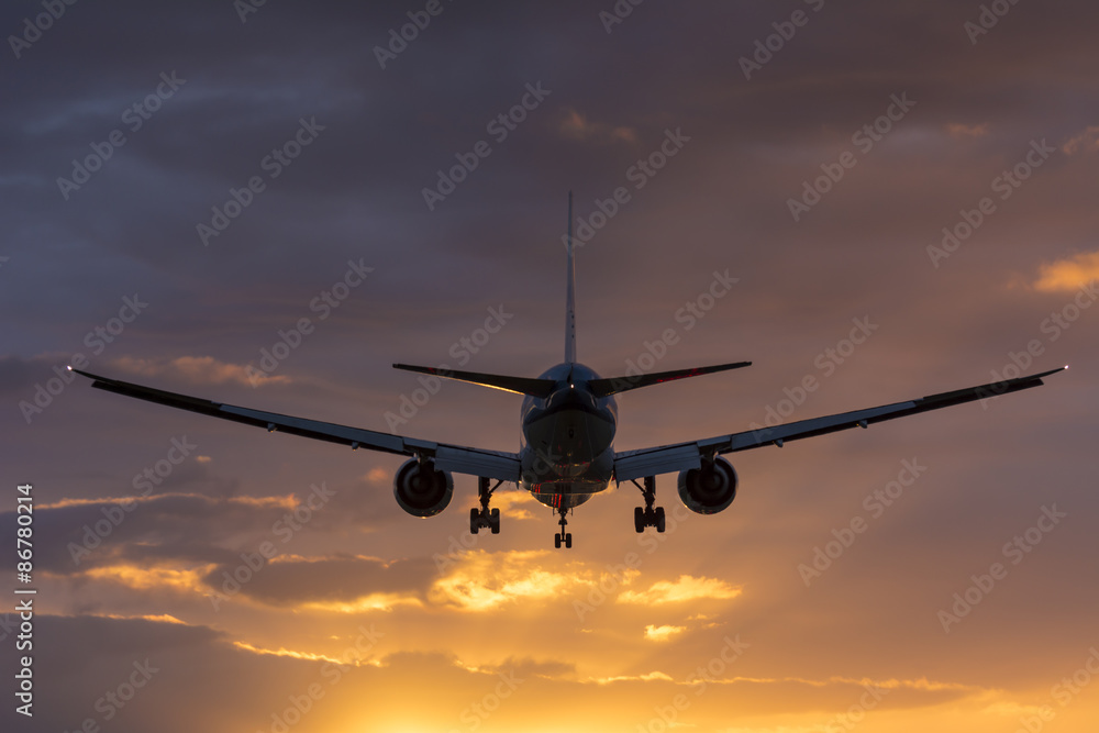 Plane is flying towards the runway. Cloudy orange sky. Plane is flying towards the runway. Cloudy orange sky.