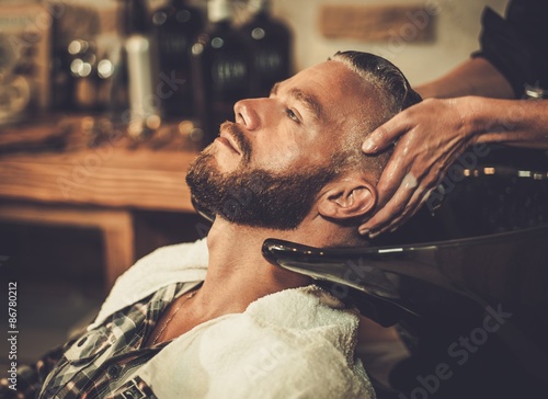 Hairstylist washing client's hair in barber shop