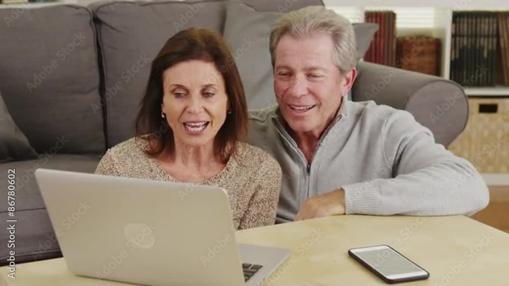 Elderly couple kiss and use laptop in the living room Elderly couple kiss and use laptop in the living room