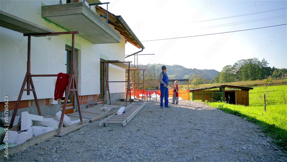Two boys playing in work clothes with helmet behind the house Two boys playing in work clothes with helmet behind the house
