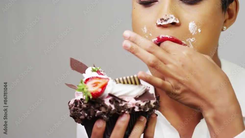 Black woman making a mess eating a huge fancy dessert