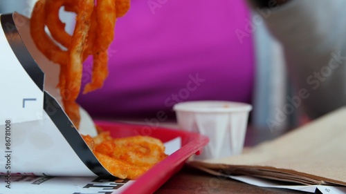 Woman eating curly fries at a fast food restaurant photo