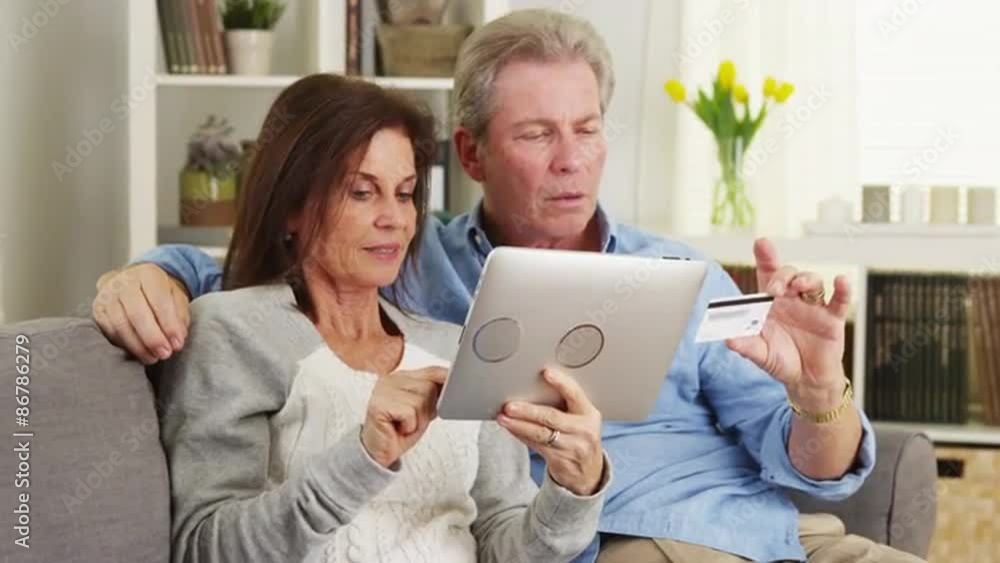 Happy senior couple making a purchase on tablet Happy senior couple making a purchase on tablet