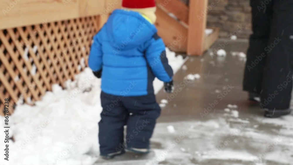 a woman and toddler shovels snow off driveway a woman and toddler shovels snow off driveway