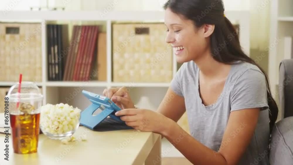 Hispanic woman laughing and using tablet on coffee table Hispanic woman laughing and using tablet on coffee table