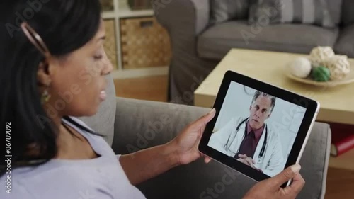 Senior african patient listening to doctor talk on tablet photo