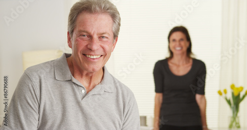 Happy Elderly couple standing in living room looking at camera