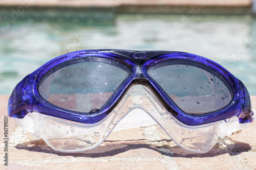 Frontal view of swim goggles on the edge of a swimming pool