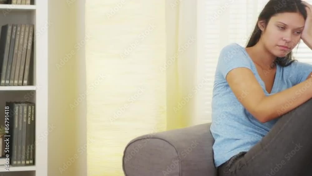Hispanic woman sitting on couch thinking Hispanic woman sitting on couch thinking