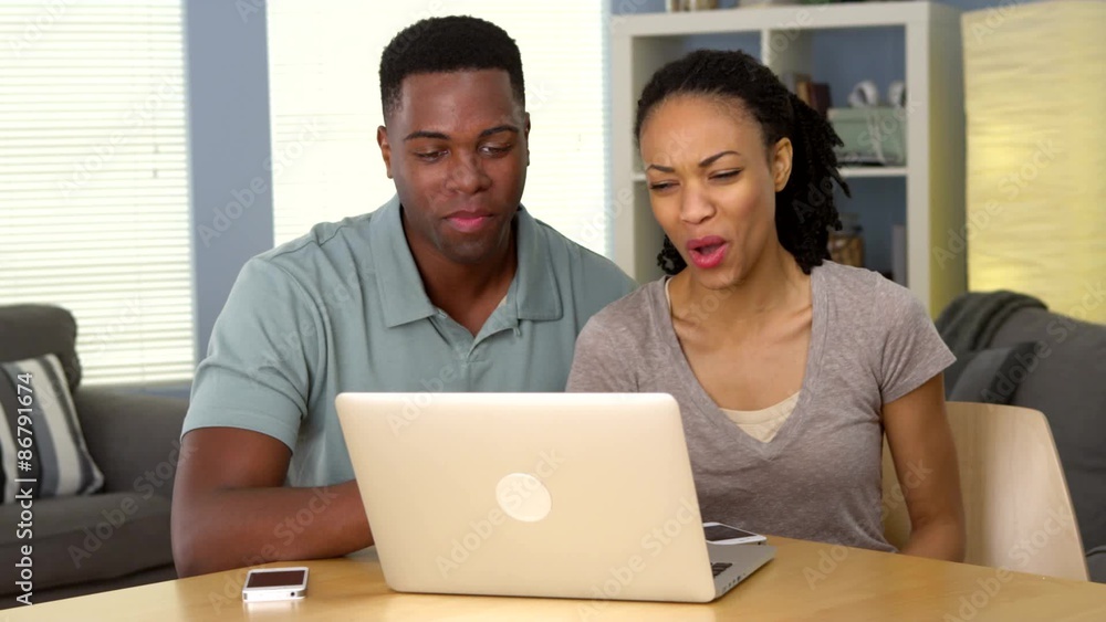 Happy young black couple laughing and watching funny video on laptop Happy young black couple laughing and watching funny video on laptop