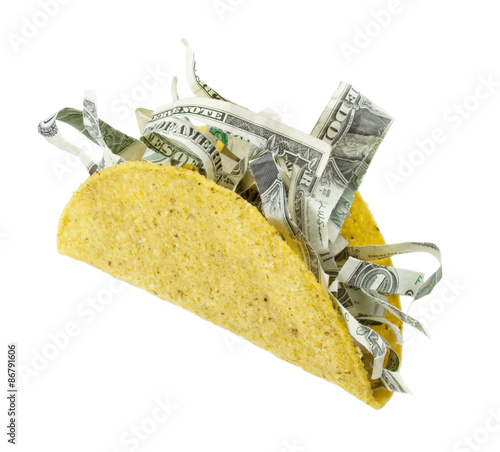 Taco with Shredded Money – A crispy corn tortilla taco shell with shredded money inside. Great concept art for the high cost of living, expensive food, GMOs, etc. Isolated on white with clipping path.