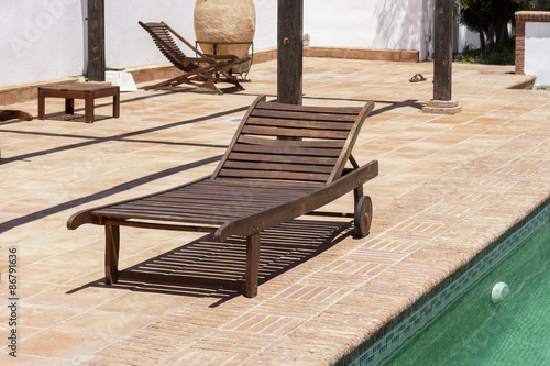 Wooden sun recliner beside a swimming pool © Alonso Aguilar