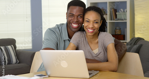 Happy young black couple with laptop and bills