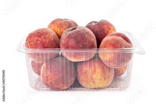Box or punnet of fresh ripe organic peaches isolated on white background