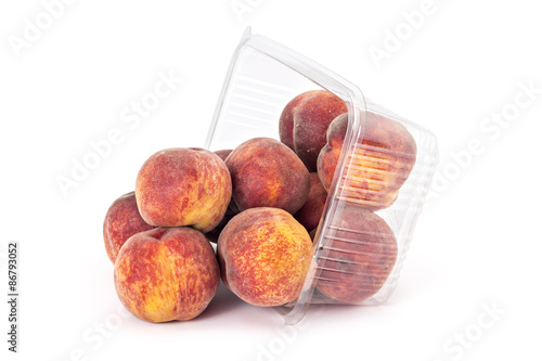 Box or punnet and spilled fresh ripe organic peaches isolated on white background