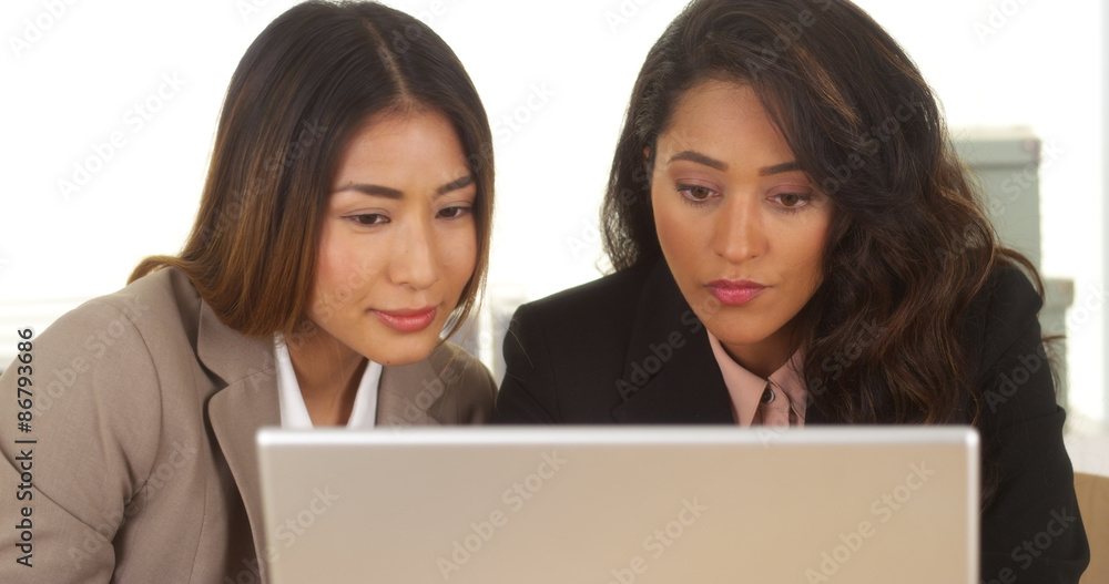 Mixed race businesswomen working on laptop Mixed race businesswomen working on laptop