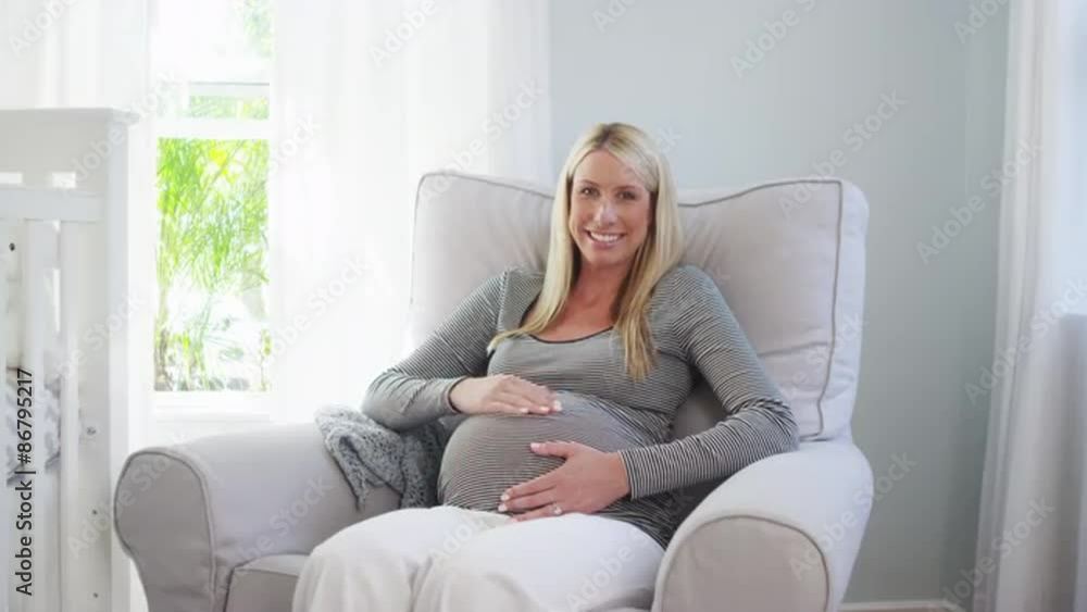 Happy pregnant woman sitting in nursery smiling Happy pregnant woman sitting in nursery smiling