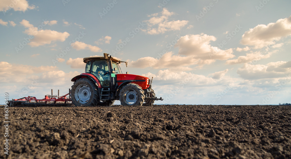 Farmer in tractor preparing land with seedbed cultivator Farmer in tractor preparing land with seedbed cultivator