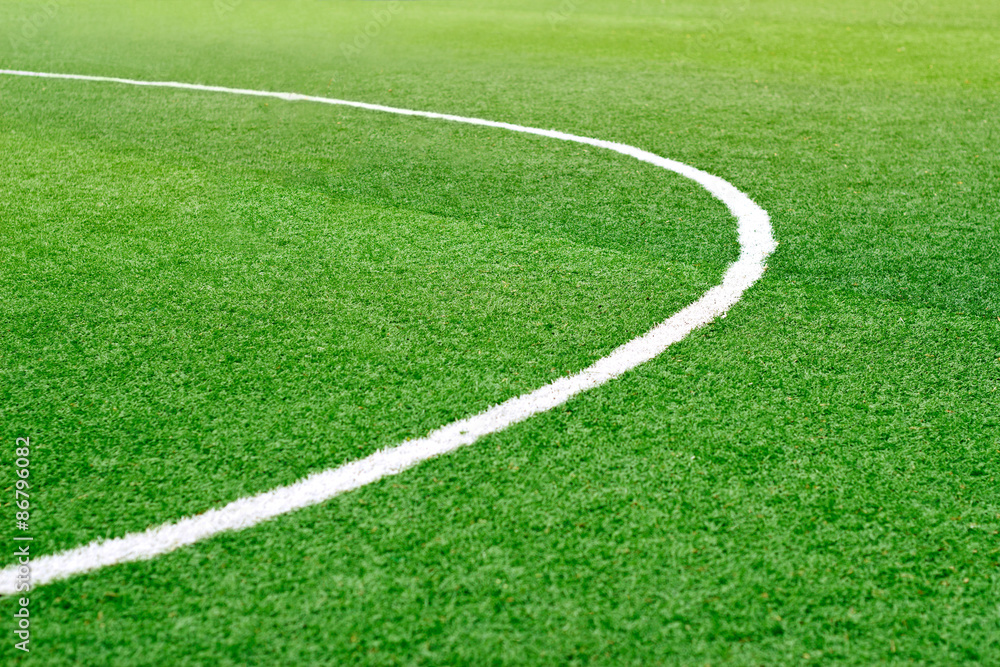 Green soccer field grass with white mark line, soft focus