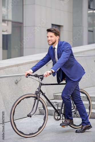 Pleasant businessman standing with bicycle 
