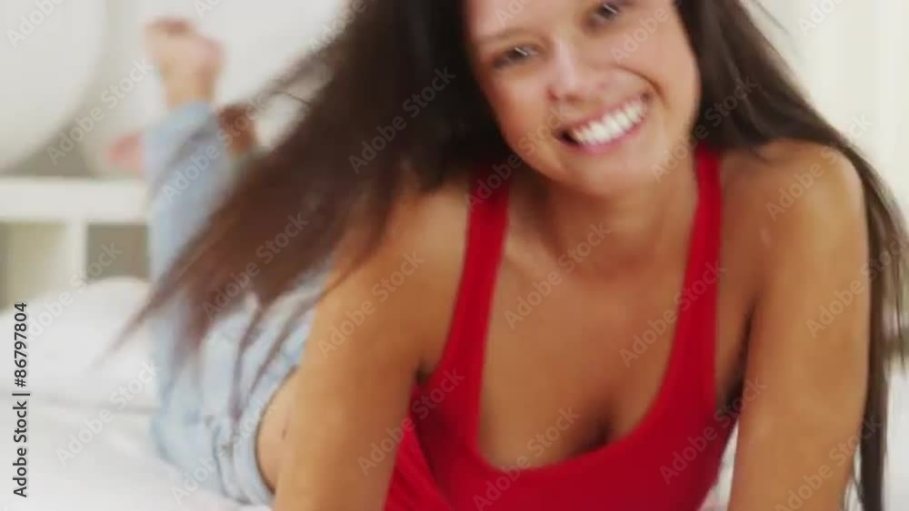 Hispanic woman lying on bed smiling and laughing Hispanic woman lying on bed smiling and laughing