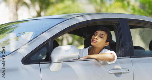 Black woman in car looking around and checking hair in mirror © rocketclips
