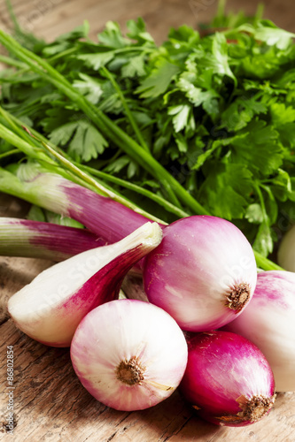 Fresh organic red onions with the stems on an old wooden table,