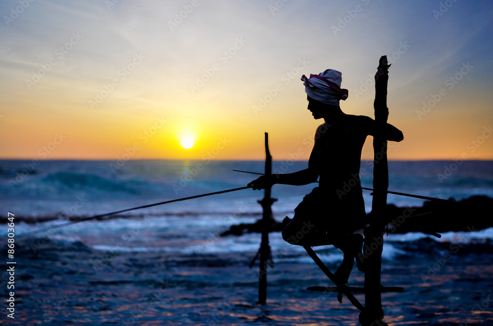 Fototapeta premium In Sri Lanka, a local fisherman is fishing in unique style in the evening.